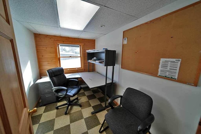 office space with a paneled ceiling, wooden walls, and tile patterned floors