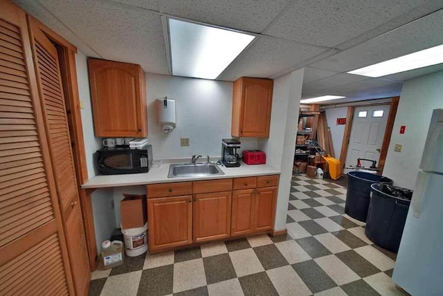 kitchen with black microwave, a sink, light countertops, freestanding refrigerator, and tile patterned floors