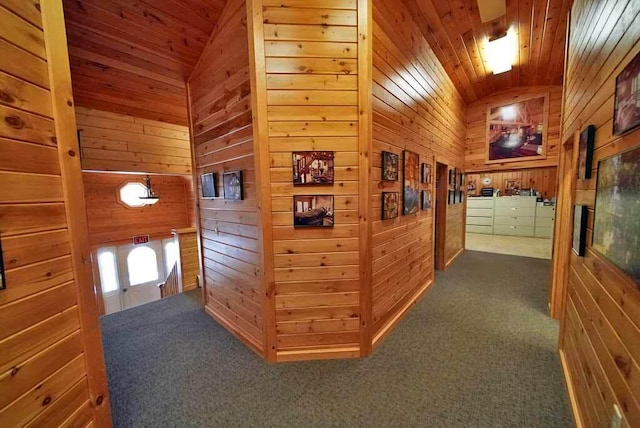 corridor with dark colored carpet, wooden ceiling, vaulted ceiling, and wooden walls