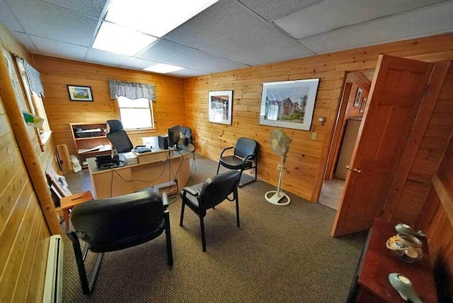 home office with carpet floors, baseboard heating, a paneled ceiling, and wooden walls