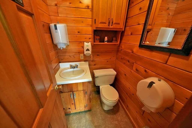 half bathroom featuring wood walls, vanity, and toilet