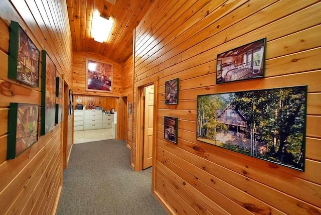 hallway featuring wood walls, wood ceiling, vaulted ceiling, and carpet