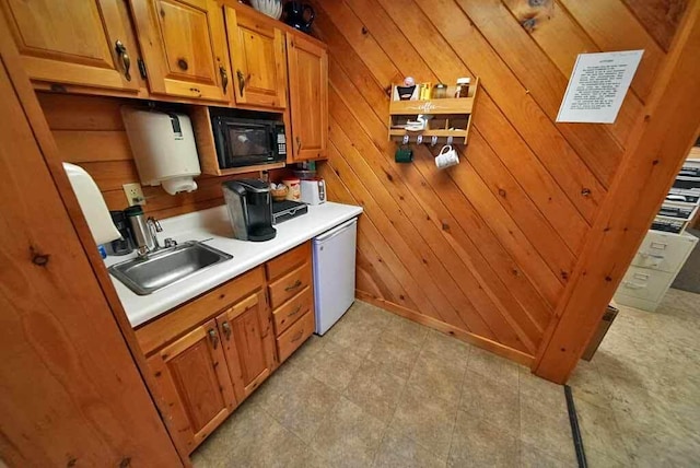 kitchen with black microwave, a sink, wood walls, and dishwashing machine