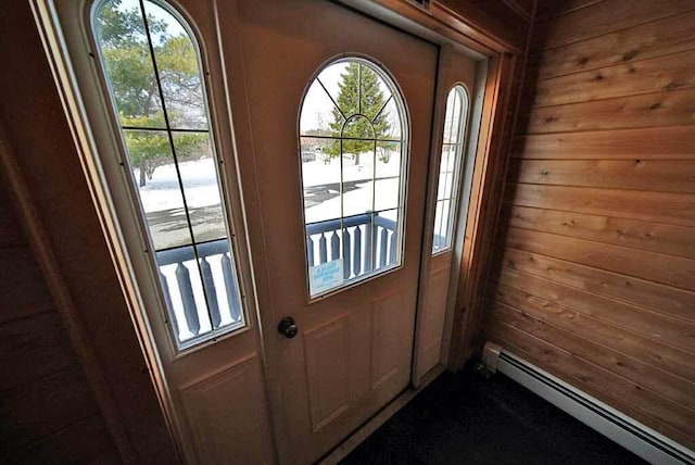 doorway with wood walls and a baseboard heating unit