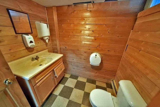 bathroom with wood walls, vanity, toilet, and tile patterned floors