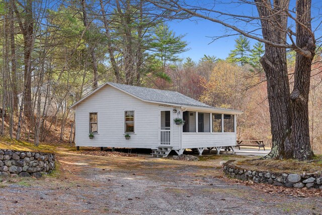 view of front of house featuring a shingled roof and a sunroom