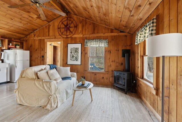 living room with wooden walls, plenty of natural light, light wood-style floors, and vaulted ceiling