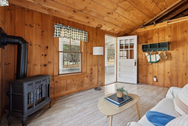 living area with a wood stove, wood finished floors, lofted ceiling, wooden walls, and wood ceiling