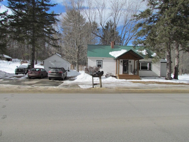 view of front of property featuring metal roof, a chimney, and an outdoor structure