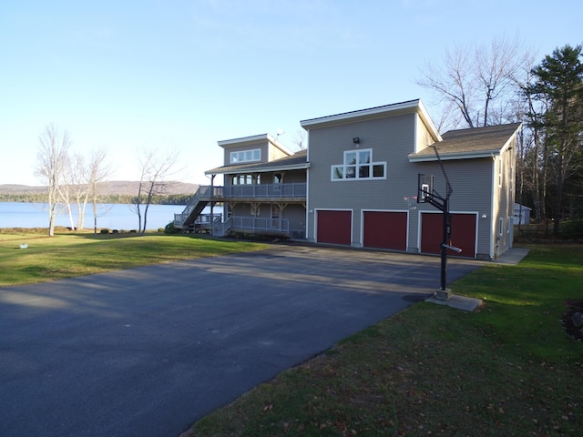 exterior space with a water view, a garage, stairway, and aphalt driveway