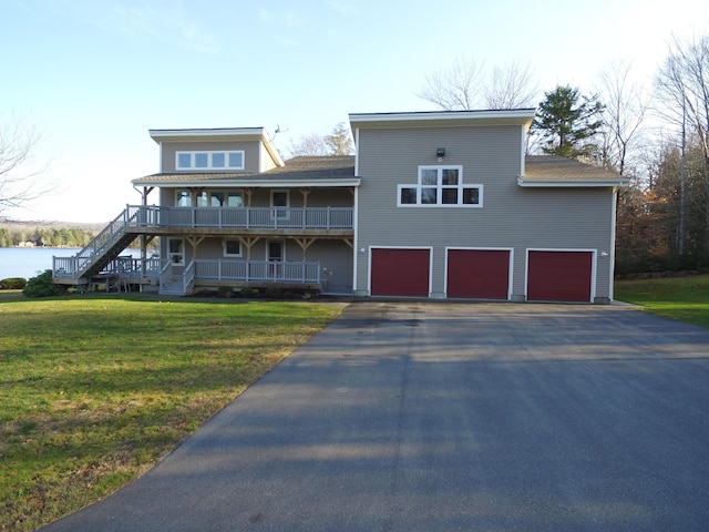 view of front of home featuring driveway, an attached garage, a water view, stairs, and a front yard