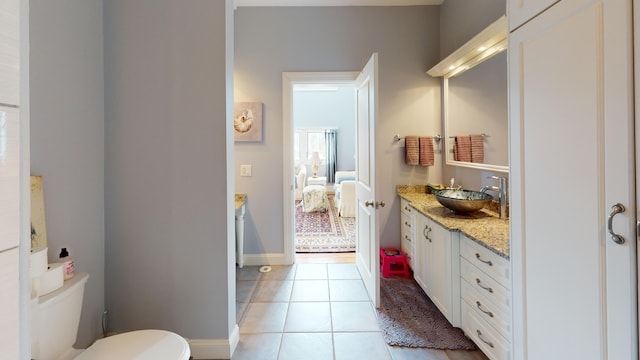 ensuite bathroom featuring toilet, ensuite bathroom, vanity, tile patterned flooring, and baseboards