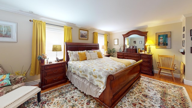 bedroom with light wood-style floors, ornamental molding, and baseboards