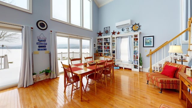 dining space featuring light wood-type flooring, stairway, ornamental molding, and a wall mounted air conditioner