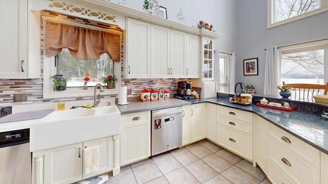 kitchen with stainless steel dishwasher, backsplash, light tile patterned flooring, and a sink