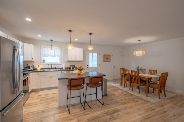 46 Firefly Ln, Bangor, ME 04401 - kitchen featuring appliances with stainless steel finishes, dark countertops, a kitchen island, a breakfast bar, and white cabinetry