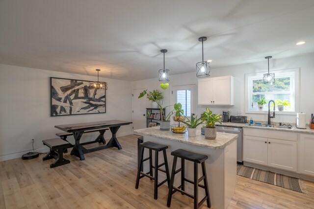 46 Firefly Ln, Bangor, ME 04401 - kitchen featuring dishwasher, a kitchen island, light wood-style flooring, white cabinetry, and a kitchen bar