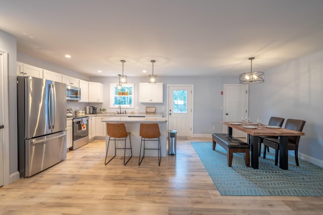 46 Firefly Ln, Bangor, ME 04401 - kitchen featuring stainless steel appliances, white cabinetry, a center island, a breakfast bar area, and light wood-style flooring