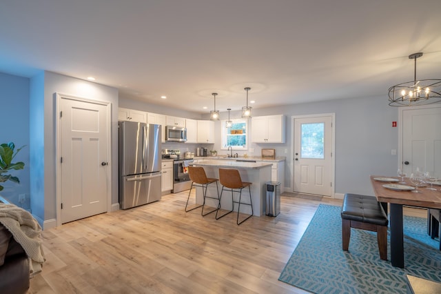 46 Firefly Ln, Bangor, ME 04401 - kitchen with appliances with stainless steel finishes, white cabinets, a center island, light wood-style flooring, and a breakfast bar