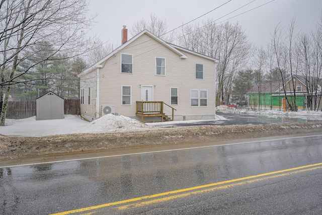 view of front facade with a storage shed, an outdoor structure, fence, and a chimney