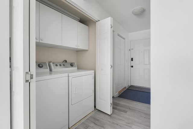 washroom with light wood-style floors, cabinet space, washer and clothes dryer, and a textured ceiling