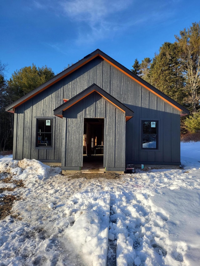 snow covered structure with an outbuilding