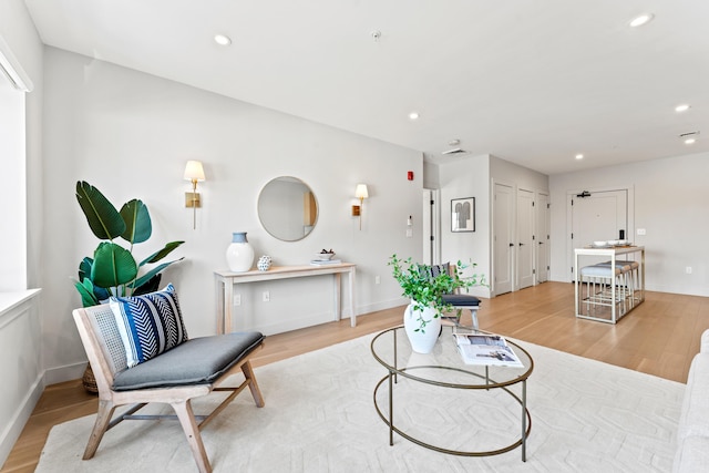 living area featuring baseboards, light wood-type flooring, and recessed lighting