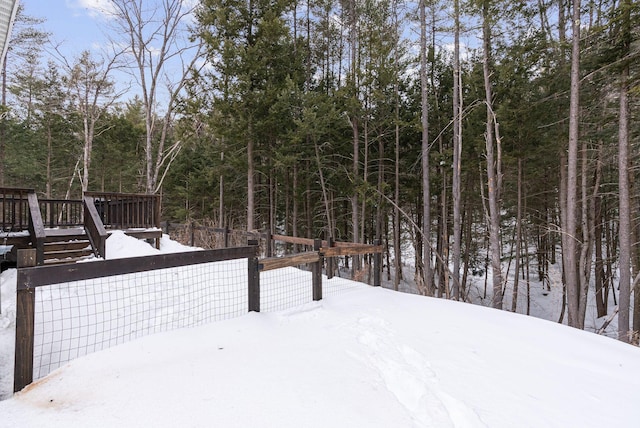 snowy yard featuring a forest view and a wooden deck