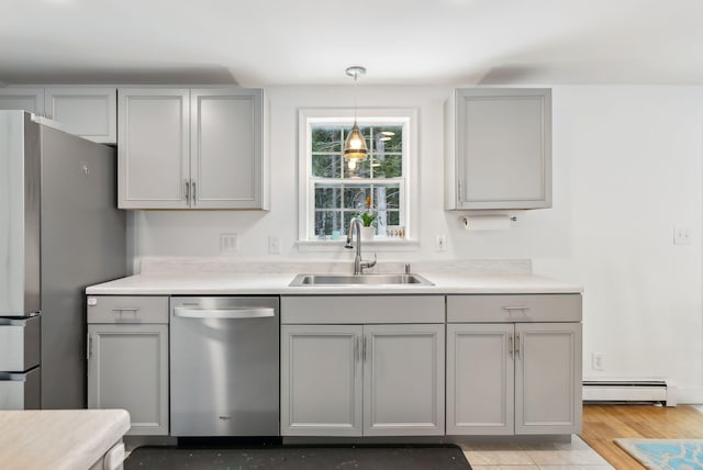 kitchen with gray cabinets, appliances with stainless steel finishes, a baseboard heating unit, and a sink