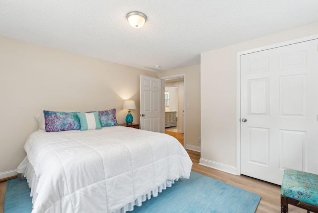 bedroom with baseboards, a textured ceiling, and light wood finished floors