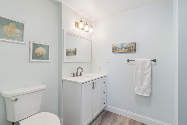 bathroom featuring vanity, toilet, wood finished floors, and baseboards