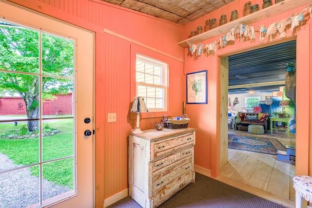 doorway featuring baseboards, an ornate ceiling, wooden walls, and hardwood / wood-style flooring