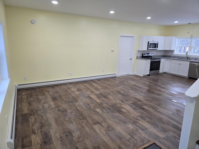 kitchen with stainless steel appliances, white cabinets, baseboard heating, tasteful backsplash, and dark wood finished floors