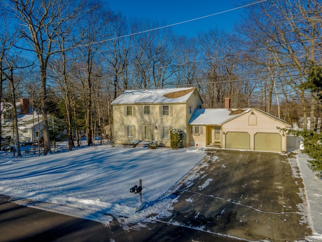 colonial home with driveway, a chimney, and an attached garage