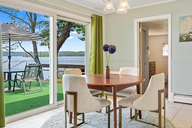 dining area featuring light tile patterned floors, wainscoting, a water view, crown molding, and a notable chandelier