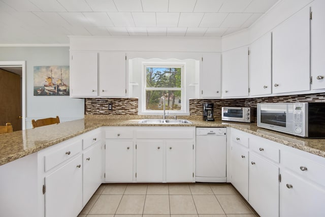 kitchen with white appliances, white cabinetry, decorative backsplash, and a sink