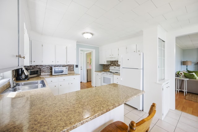 kitchen featuring tasteful backsplash, white cabinets, light tile patterned flooring, white appliances, and a peninsula