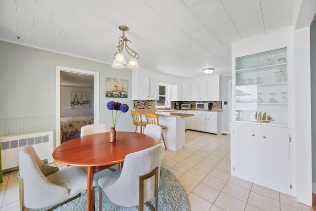 dining area with light tile patterned floors, radiator heating unit, crown molding, and wainscoting