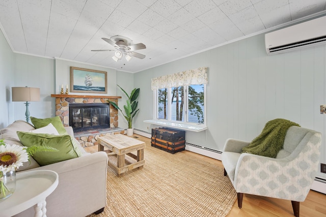 living area featuring a stone fireplace, a baseboard heating unit, wood finished floors, ornamental molding, and a wall mounted air conditioner