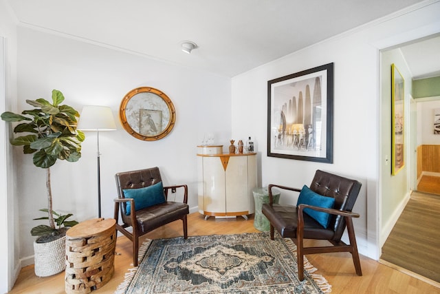 living area featuring baseboards, crown molding, and light wood finished floors