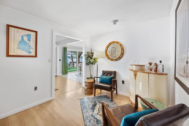 sitting room with ornamental molding, wood finished floors, and baseboards