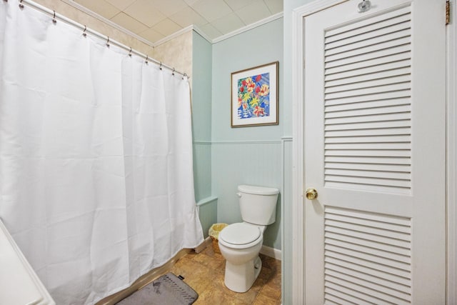 full bath with toilet, a wainscoted wall, crown molding, and a shower with shower curtain