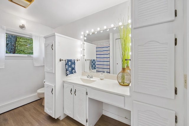 bathroom with visible vents, toilet, baseboard heating, vanity, and wood finished floors