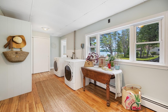 laundry area with laundry area, separate washer and dryer, a baseboard radiator, and light wood-style floors