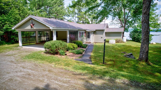 ranch-style house with dirt driveway, an attached carport, and a front yard