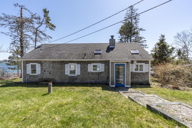 view of front facade with roof with shingles, a chimney, and a front lawn