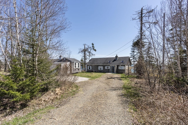 view of front of property featuring a chimney and dirt driveway