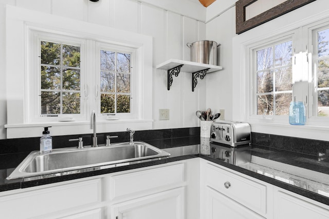 kitchen featuring dark countertops, white cabinetry, open shelves, and a sink