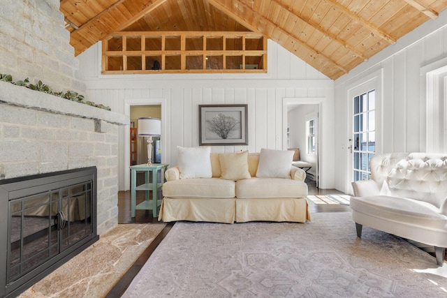 living area featuring wood ceiling, beamed ceiling, and a stone fireplace