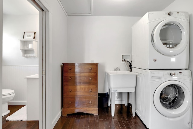 laundry area with stacked washer and dryer, laundry area, a wainscoted wall, and dark wood-style floors